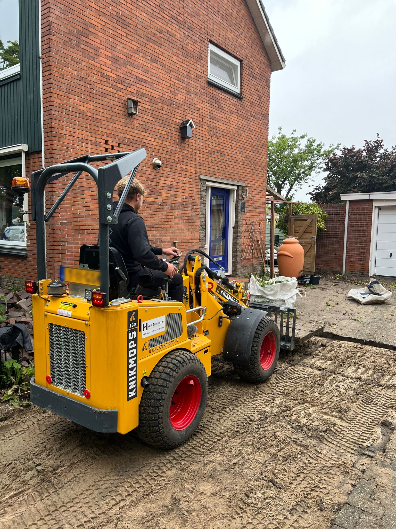 Stratenmaker op shovel bij de aanleg van een oprit